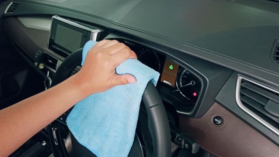 A hand cleaning a car's dashboard
