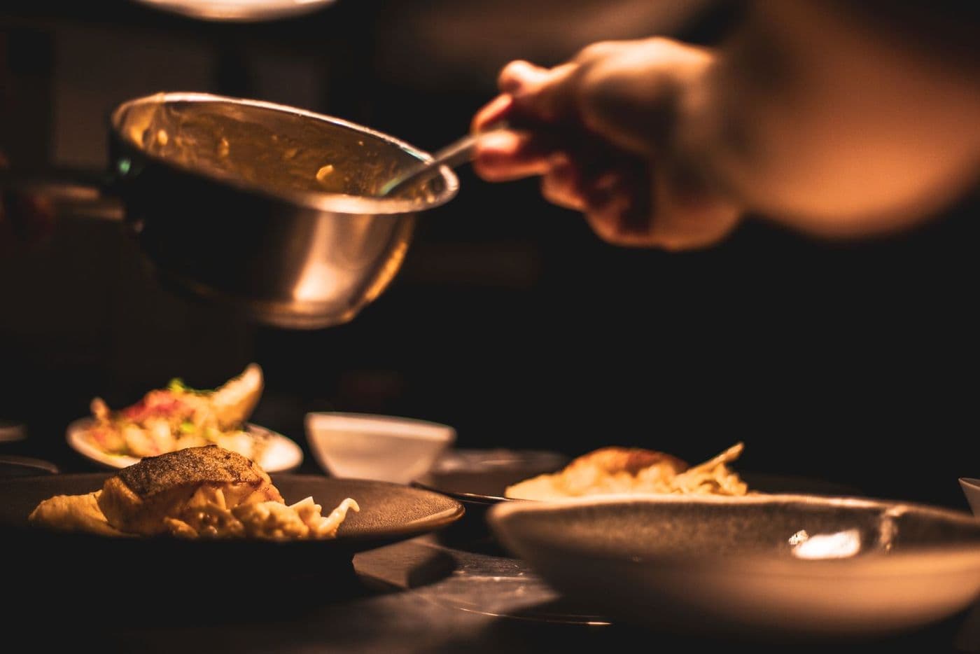 A cook plating food at the pass